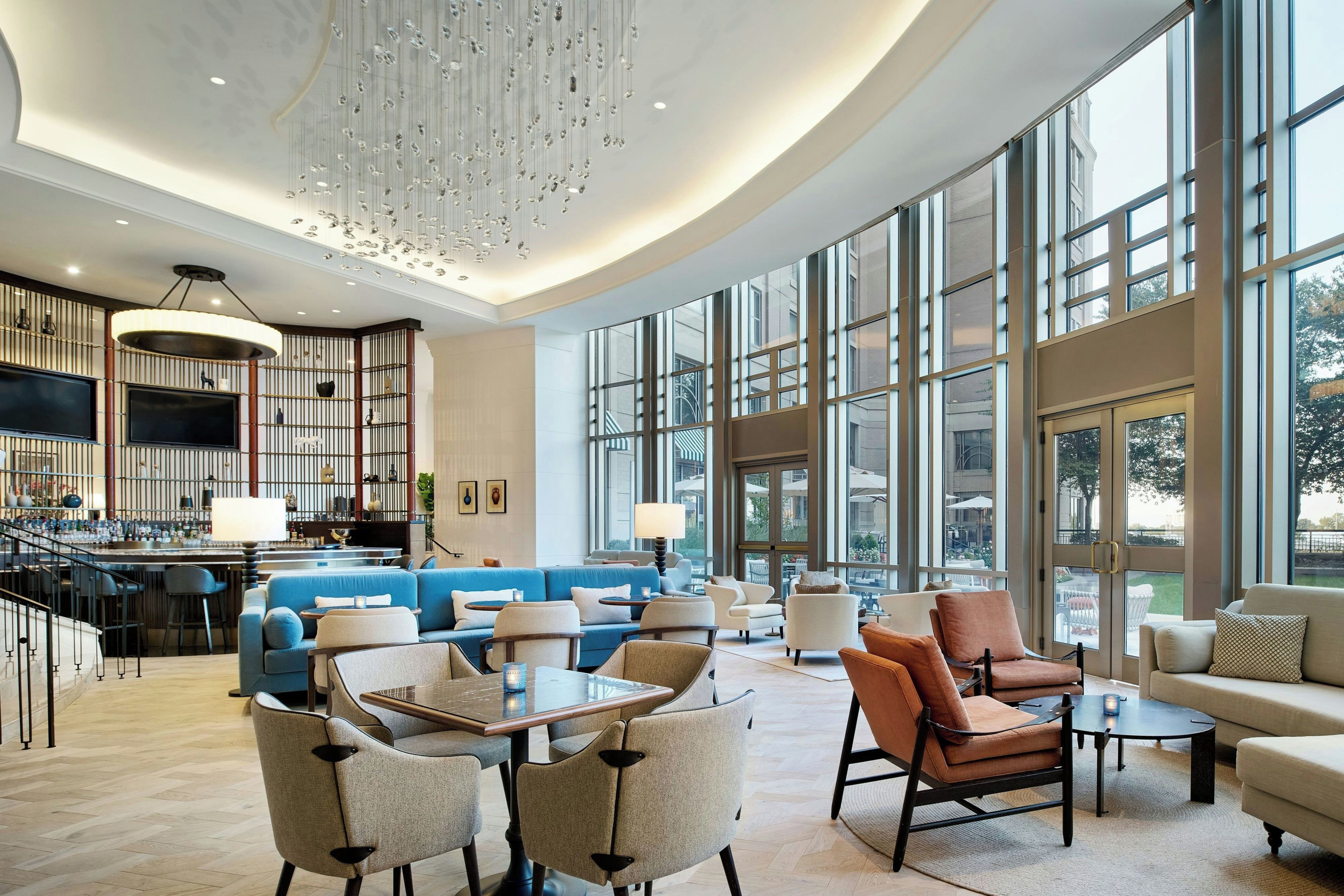 Un vaste espace salon doté d’un canapé bleu, de nombreux sièges et d’un bar avec vue sur l’extérieur grâce à de grandes fenêtres.