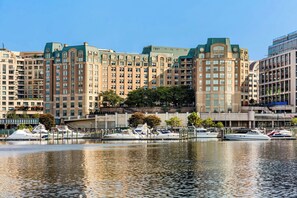 A waterfront hotel with multiple high-rise buildings, a marina with yachts, and a clear sky.