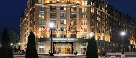 A large, multi-story hotel with a classic architectural style, featuring a prominent entrance and a well-lit facade.