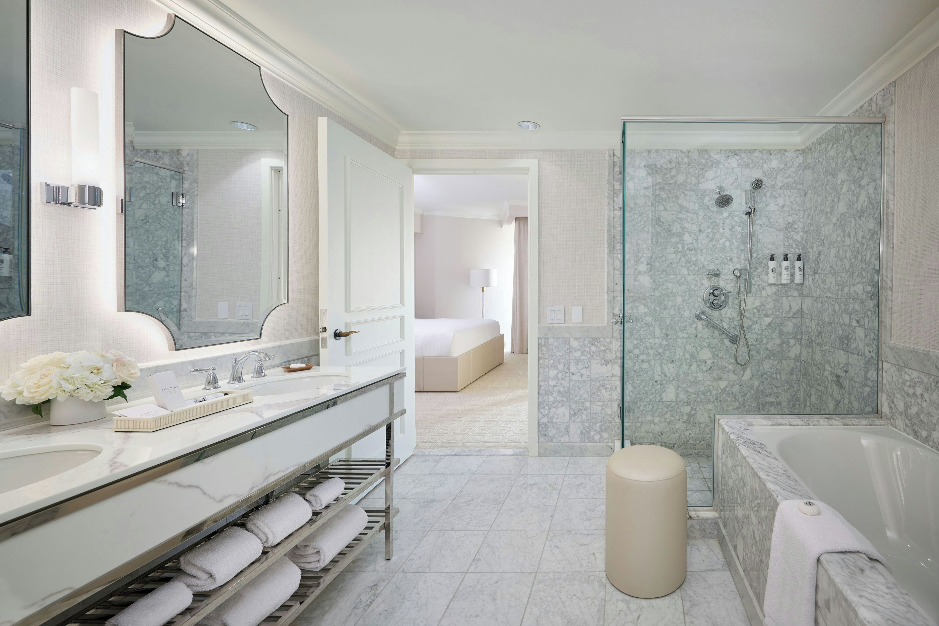 A modern bathroom with a large mirror, dual sinks, a shower area, and a bathtub.