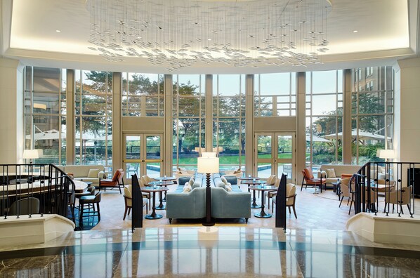 A spacious lobby with a central seating area, large windows, and a modern chandelier. - The Potomac Hotel, Autograph Collection (Washington)