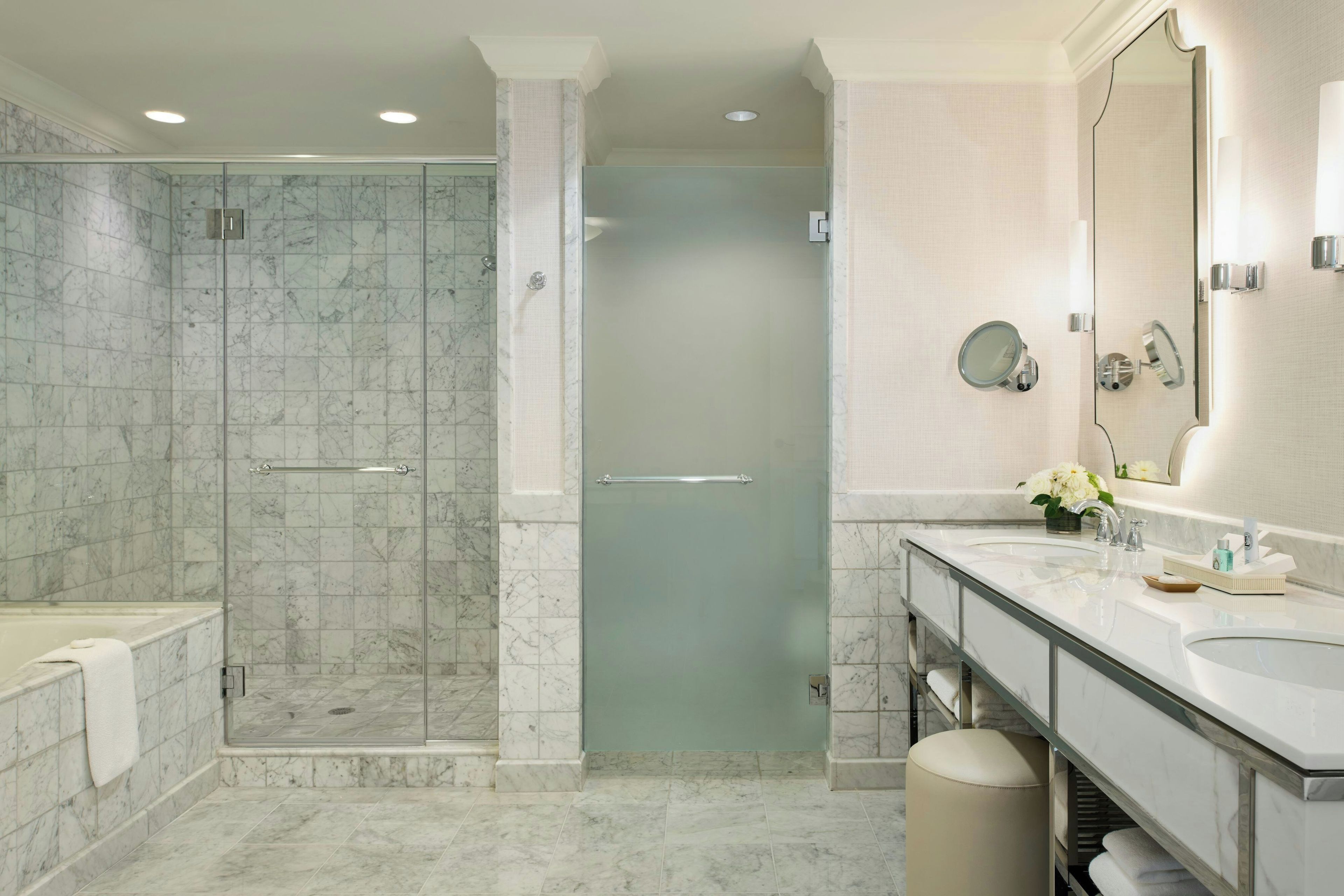 Un baño moderno con ducha envuelta en vidrio, tocador con espejo y bañera.
