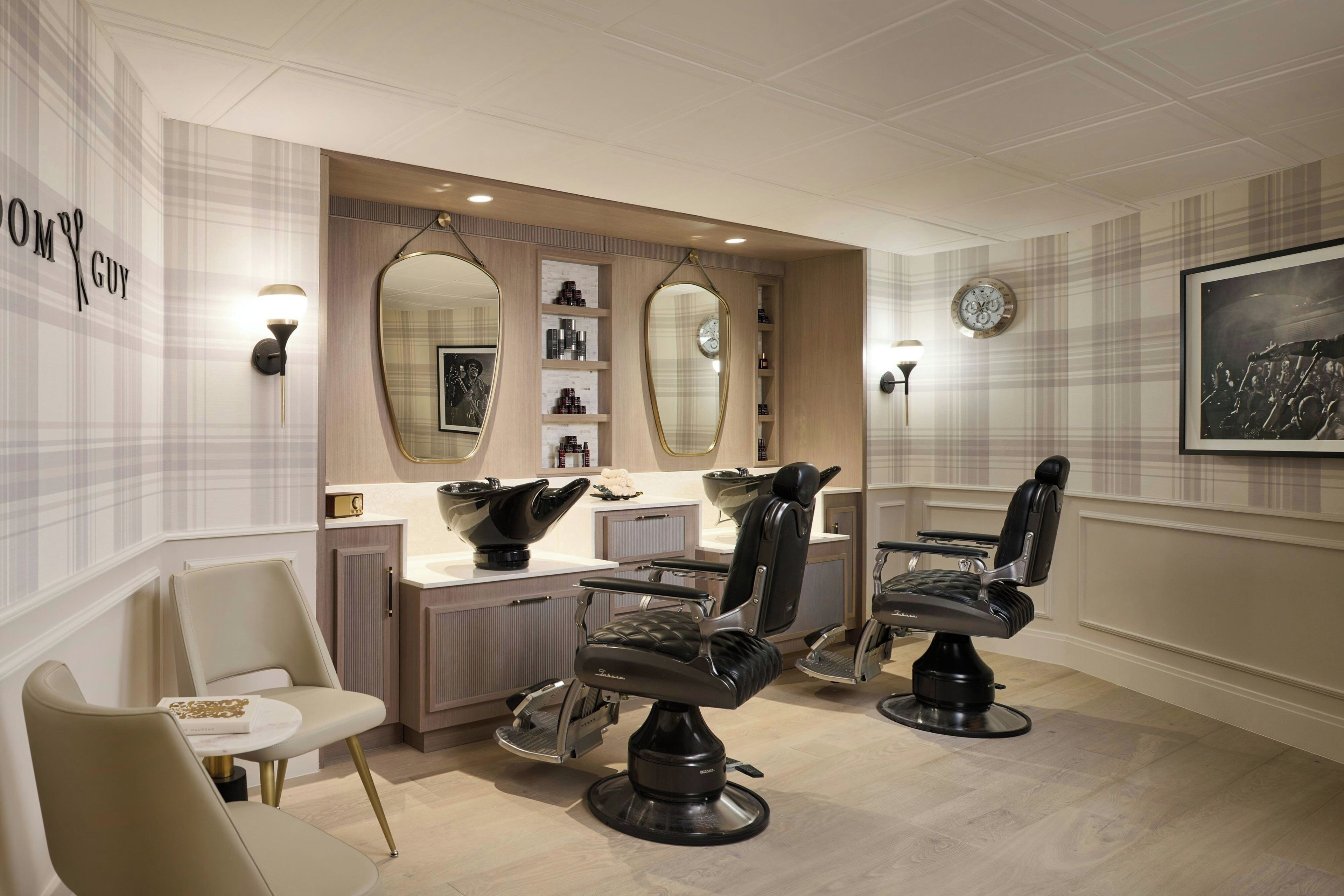 Ein moderner Friseursalon mit zwei Frisierstühlen, einem Spiegel, Regalen für Produkte und einer Wanduhr.