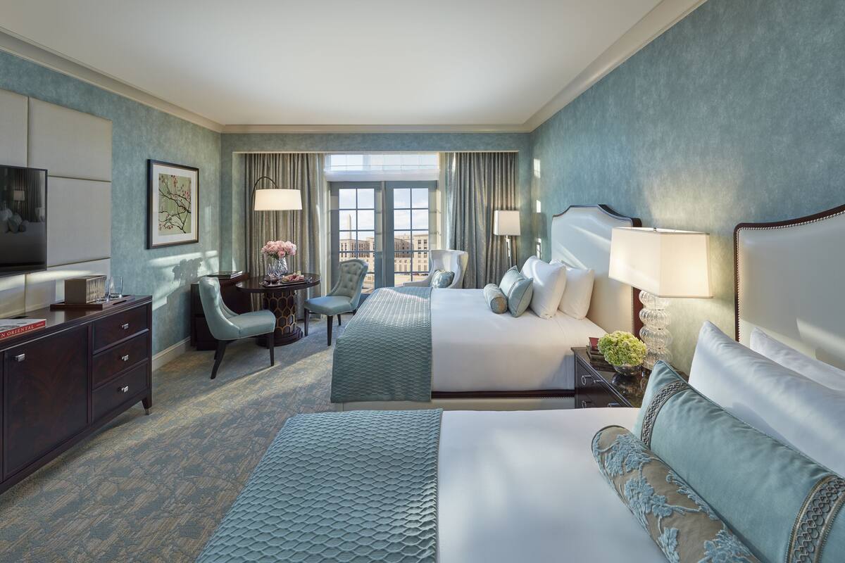 Una habitación de hotel con una cama grande, un escritorio, una silla y un televisor.
