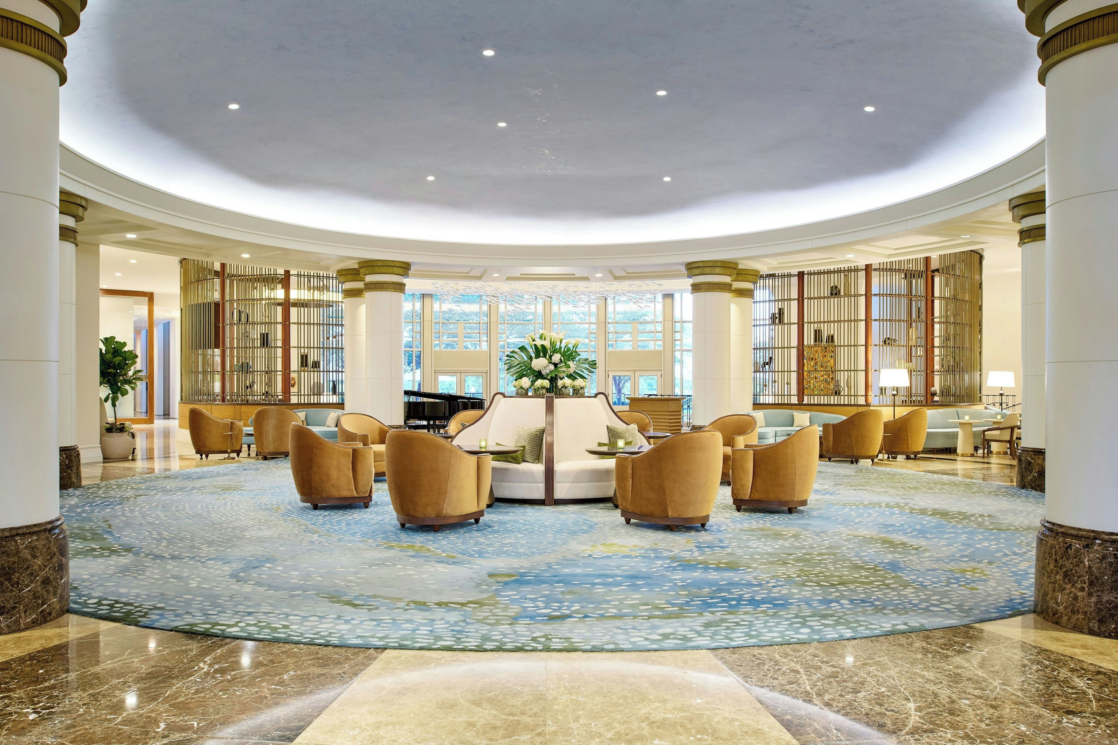 A spacious lobby with a circular marble floor, seating area, and large windows.