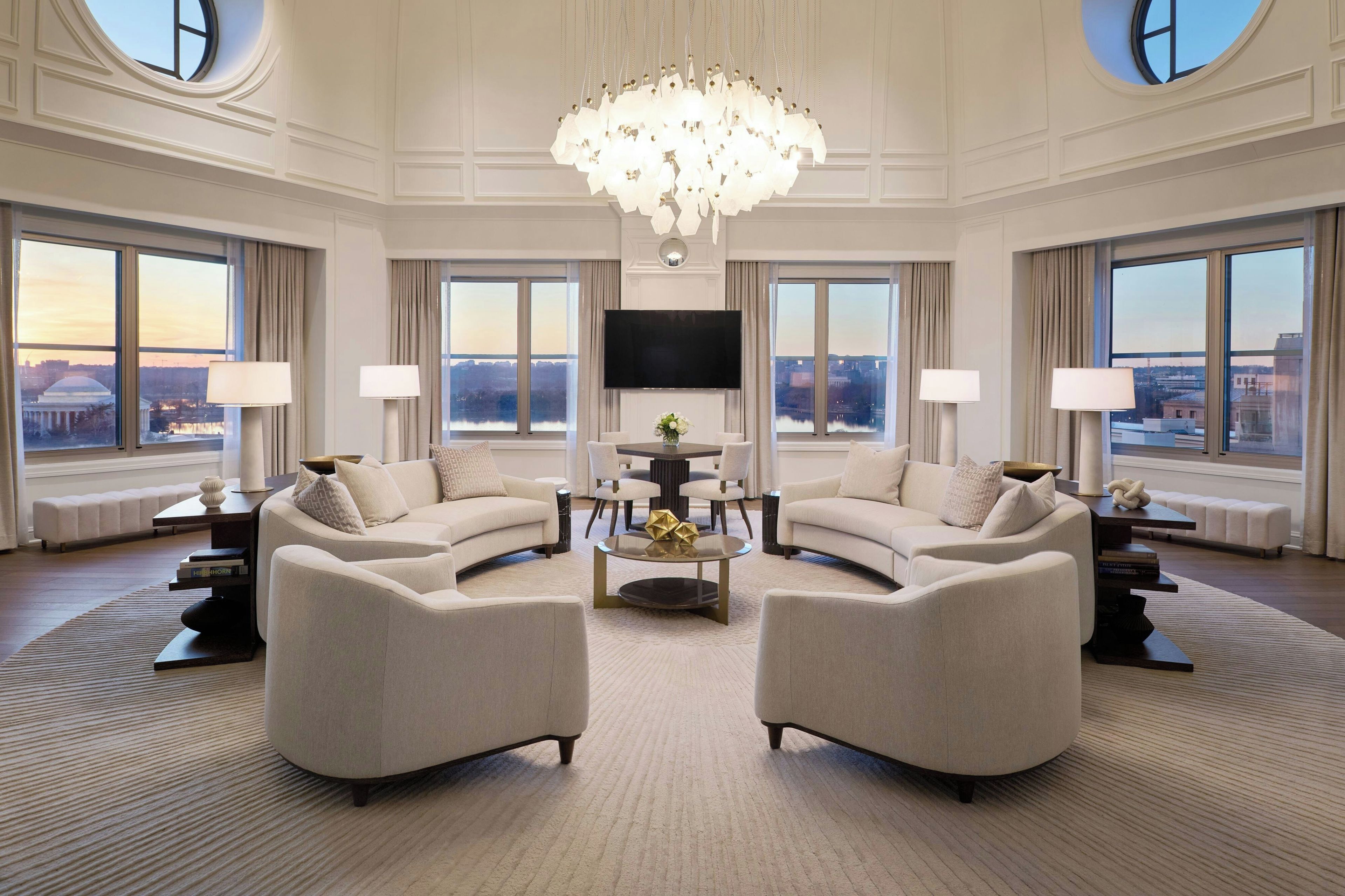 A spacious living room with a large chandelier, two sofas, a coffee table, and a flat-screen TV.