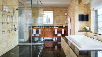 Un baño moderno con ducha de vidrio, una bañera grande y un tocador con espejo y lavamanos.