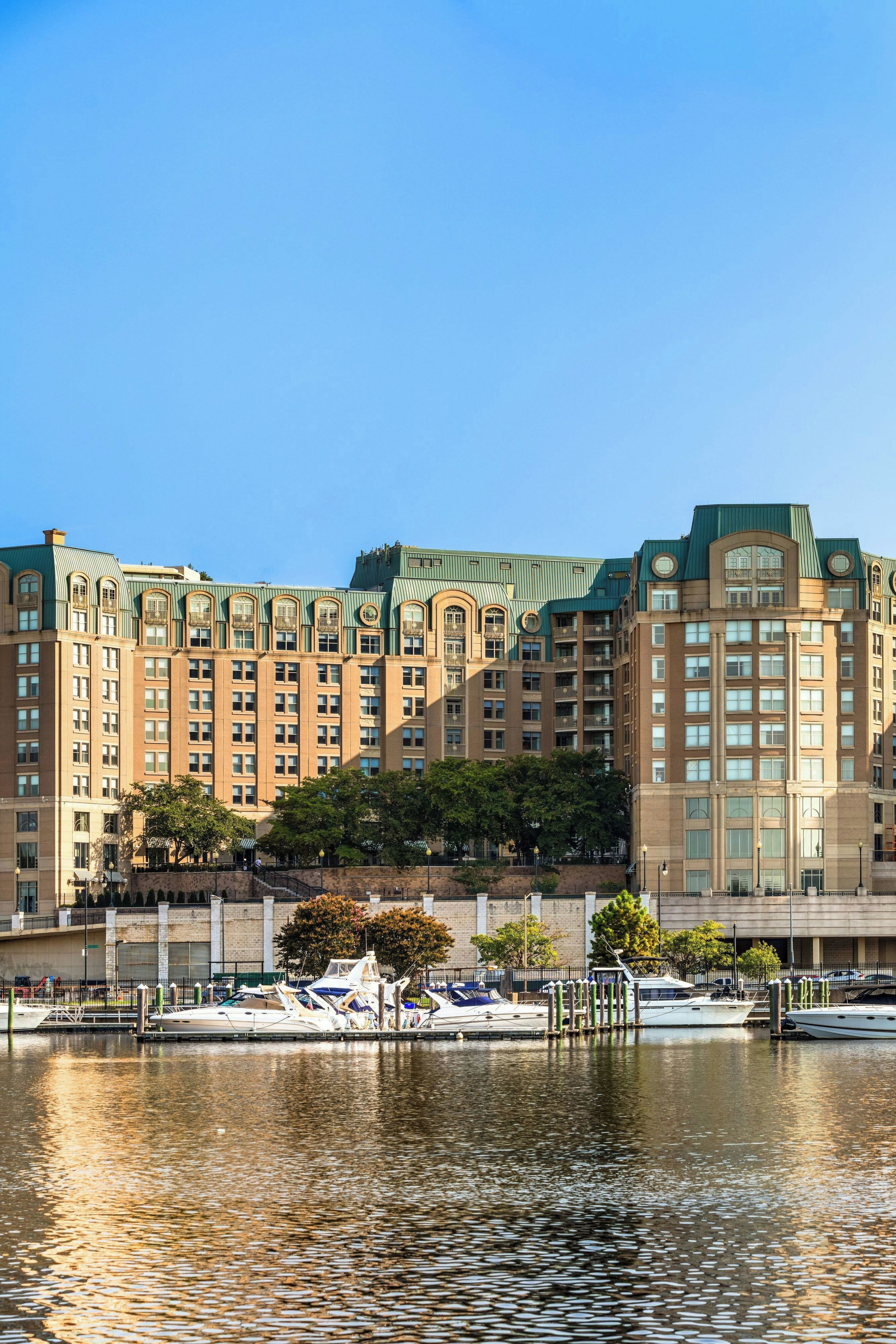 A multi-story hotel with a waterfront view, featuring balconies and a marina with boats.