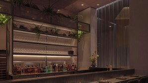 Uma área de bar com prateleiras cheias de garrafas de bebidas, copos e um vaso de planta.