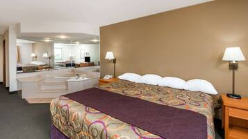 A hotel room with a large bed, a separate bathroom with a bathtub, and a mirror reflecting the room.