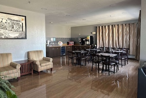 Una sala de estar moderna con un sofá, sillas y un comedor con mesas y sillas.