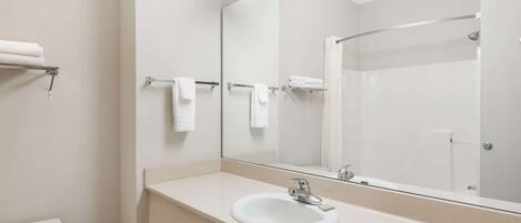 Un baño con un lavamanos blanco, un espejo y una ducha.