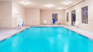 An indoor swimming pool with clear water, a changing room, and a door leading to another area.