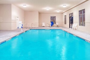 Una piscina interior con agua cristalina, un vestuario y una puerta que da a otra zona.