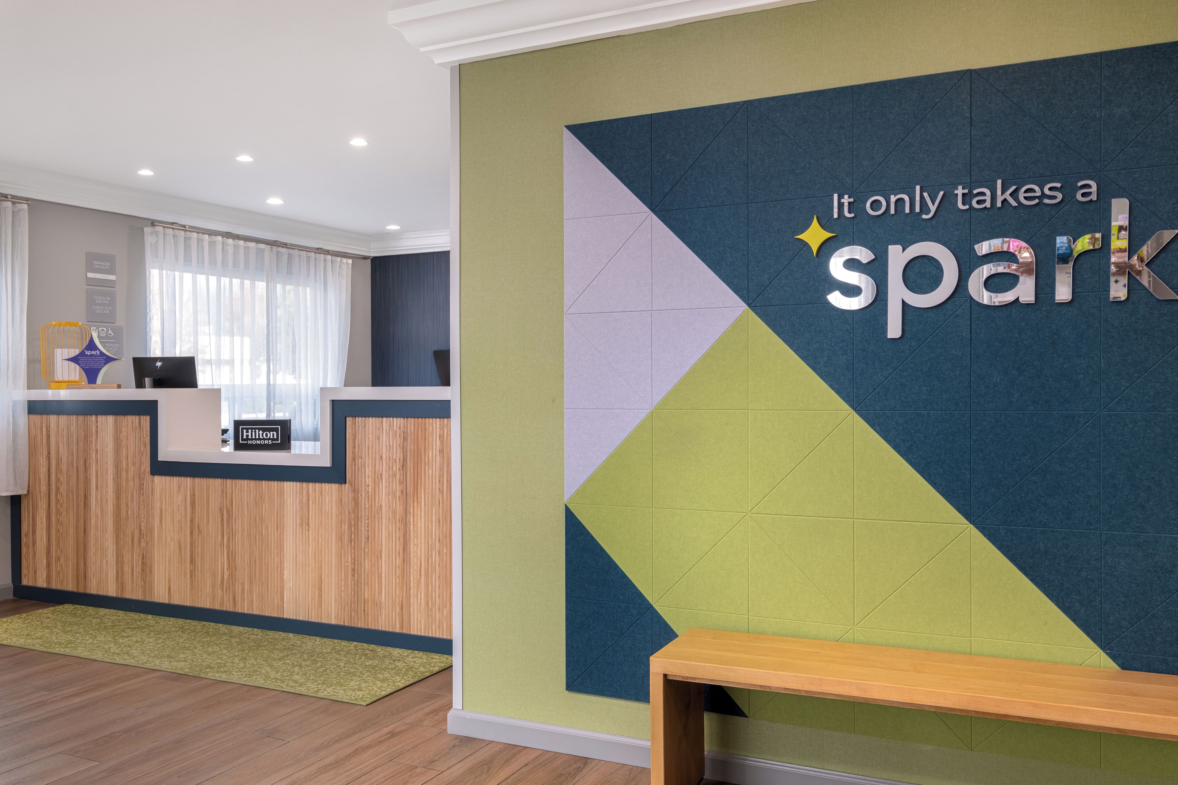 Een receptiebalie met een bord waarop staat 'It only takes a spark' en een 'Hilton Honors' bord eronder.