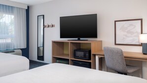 Une chambre d’hôtel comprenant un lit, un bureau avec une télévision, un four à micro-ondes et une chaise.