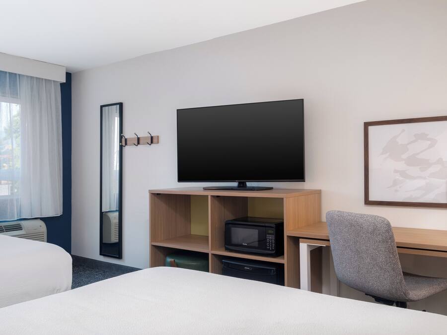Une chambre d’hôtel comprenant un lit, un bureau avec une télévision, un four à micro-ondes et une chaise.