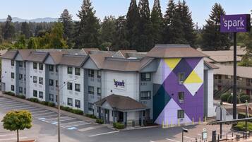 A multi-story hotel with a parking lot, a covered entrance, and a distinctive purple and yellow geometric facade.
