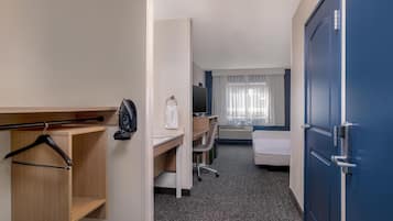 A hotel room with a desk, a bed, a wardrobe, and a TV.