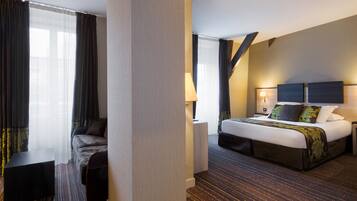 A hotel room with a bed, a sofa, a nightstand, and a window with curtains.