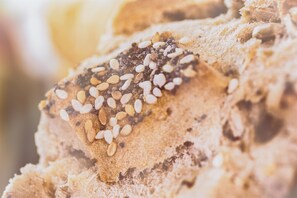 A close-up of a slice of bread with sesame seeds and other toppings.
