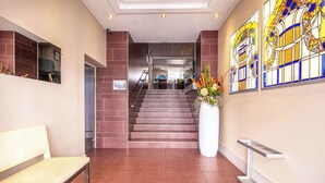 A modern lobby with a staircase, a bench, and a large vase with flowers. - Best Western Plus Hôtel Richelieu (Limoges)