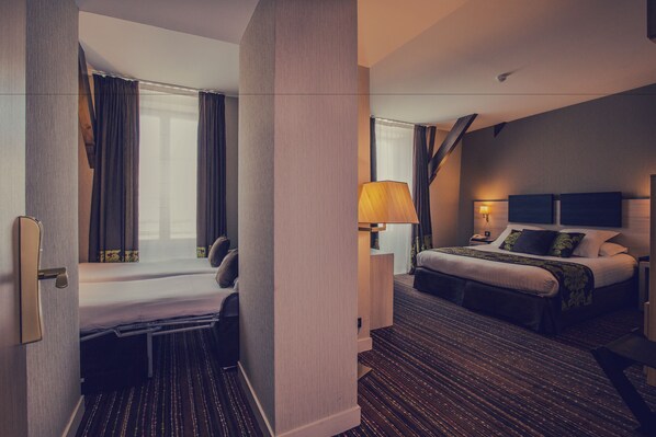 A hotel room with a bed, a desk, a chair, and a window with curtains.