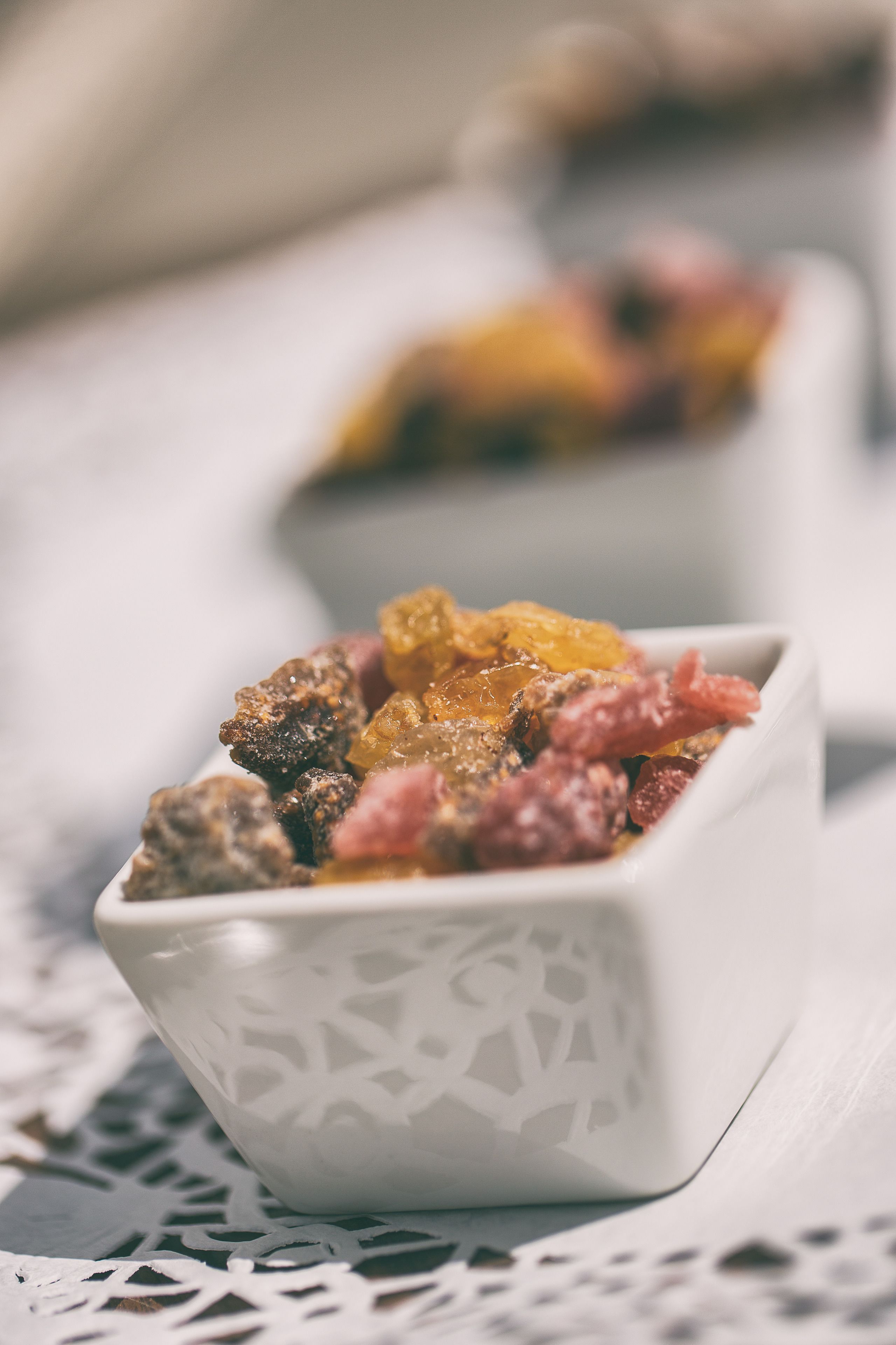 A close-up of a white bowl with a geometric pattern, filled with assorted dried fruits and nuts.