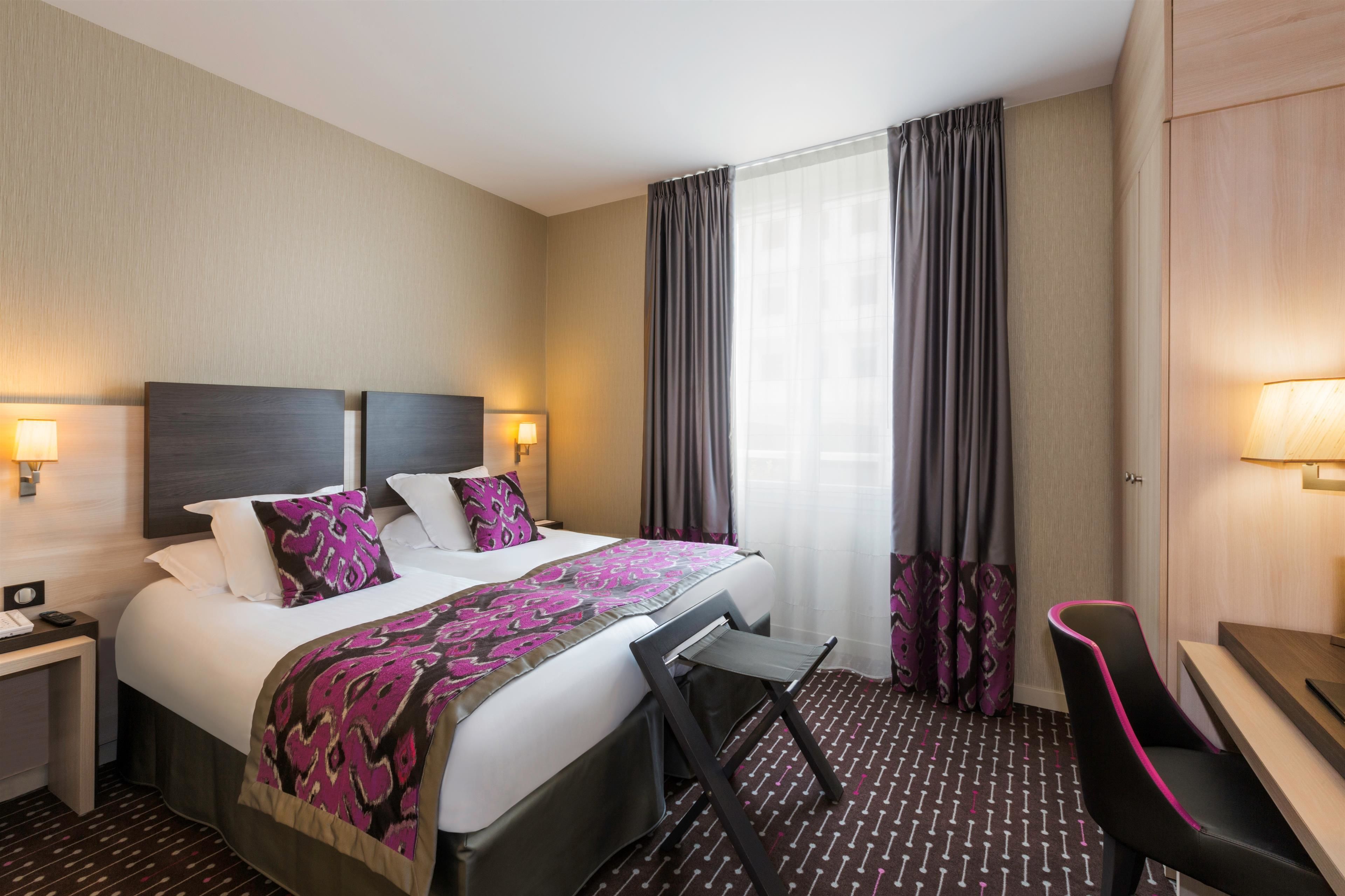 A hotel room with a bed, bedside tables, a desk, and a chair.