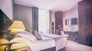 A modern hotel room with a large bed, a desk, a flat-screen TV, and a wardrobe. - Best Western Plus Hôtel Richelieu (Limoges)