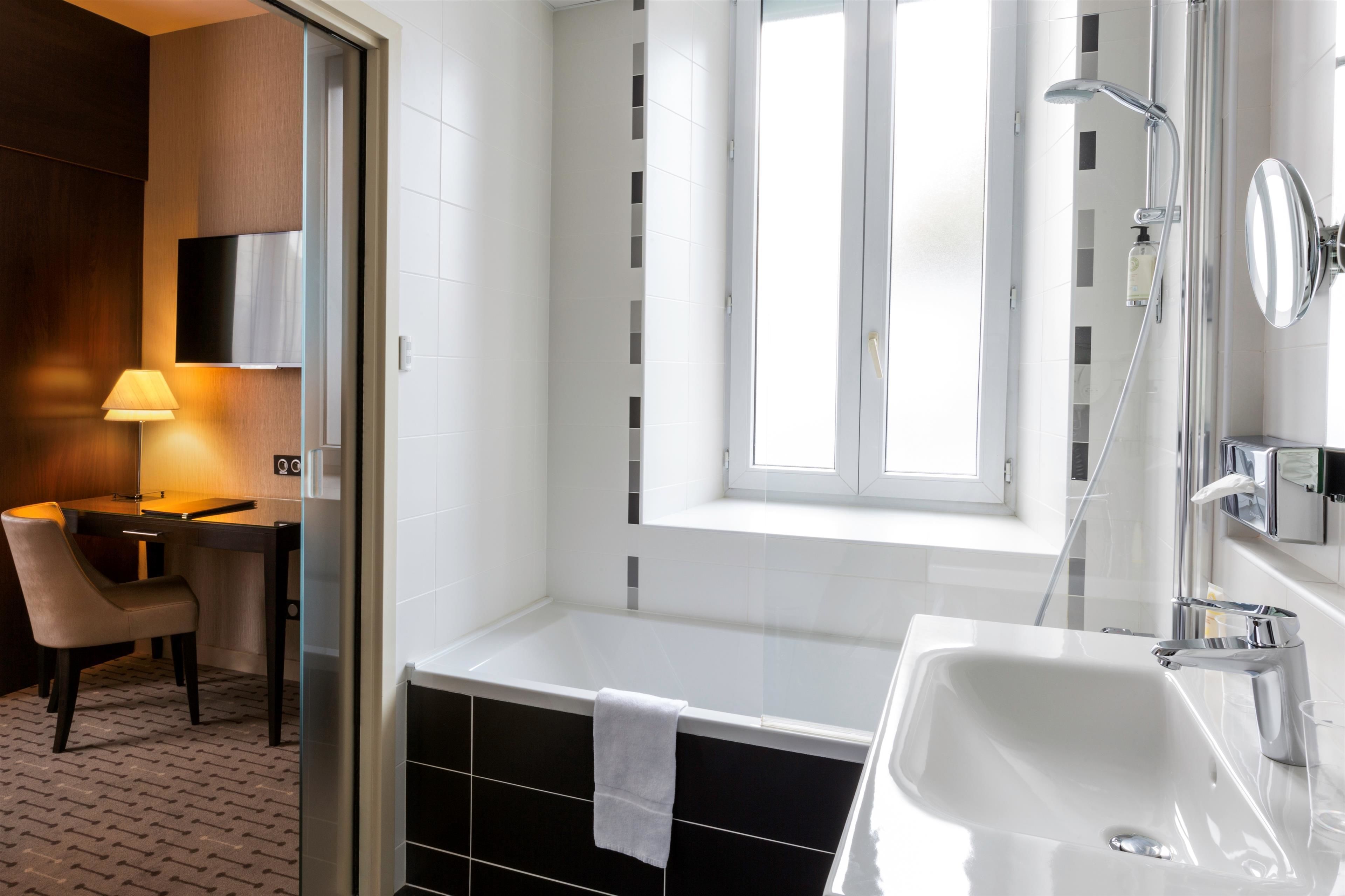 Ein modernes Badezimmer mit einer Badewanne, einem Waschbecken und einem Fenster.