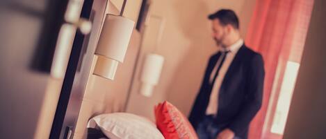 Une chambre d’hôtel avec un lit, une table de chevet, une lampe et une fenêtre avec des rideaux.