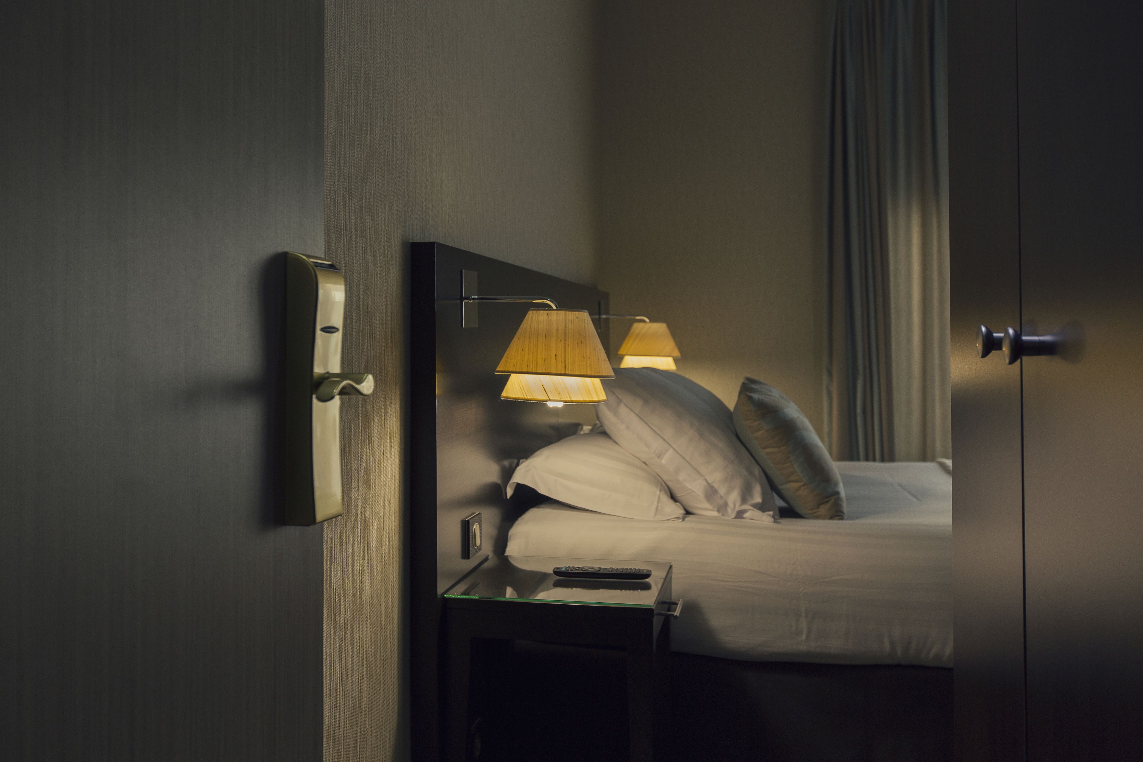 Une chambre d’hôtel avec un lit, des lampes de chevet, une table de nuit et un miroir.