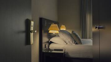A hotel room with a bed, bedside lamps, a nightstand, and a mirror.