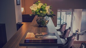 A dining table with a vase of flowers, a stack of magazines, and leather chairs. - Best Western Plus Hôtel Richelieu (Limoges)