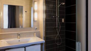 A modern bathroom with a large mirror, a sink, and a shower with a grid-patterned wall.