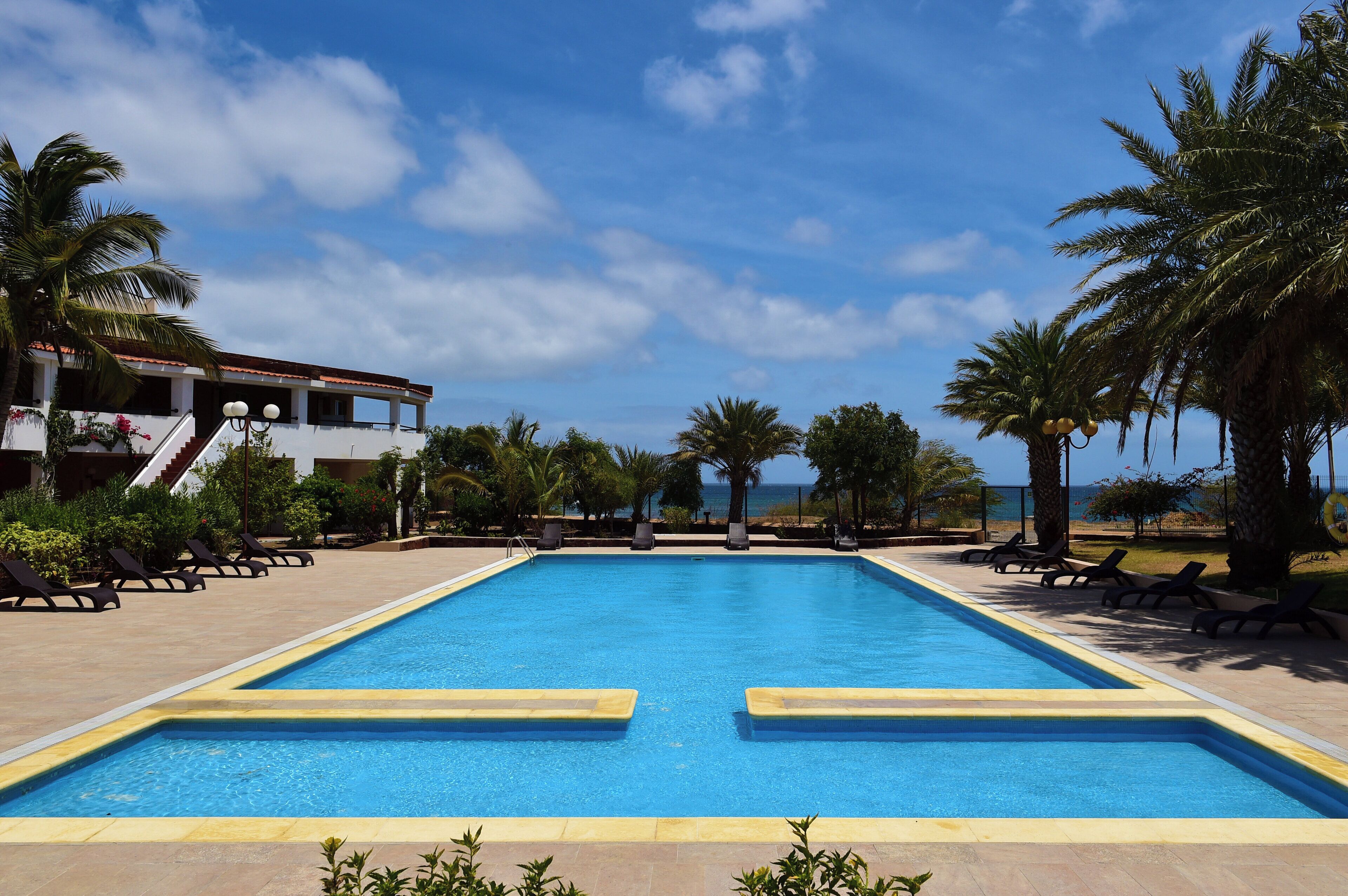 Una piscina al aire libre, sombrillas, sillones reclinables de piscina