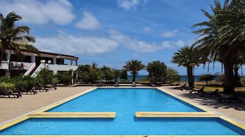 Una piscina al aire libre, sombrillas, sillones reclinables de piscina