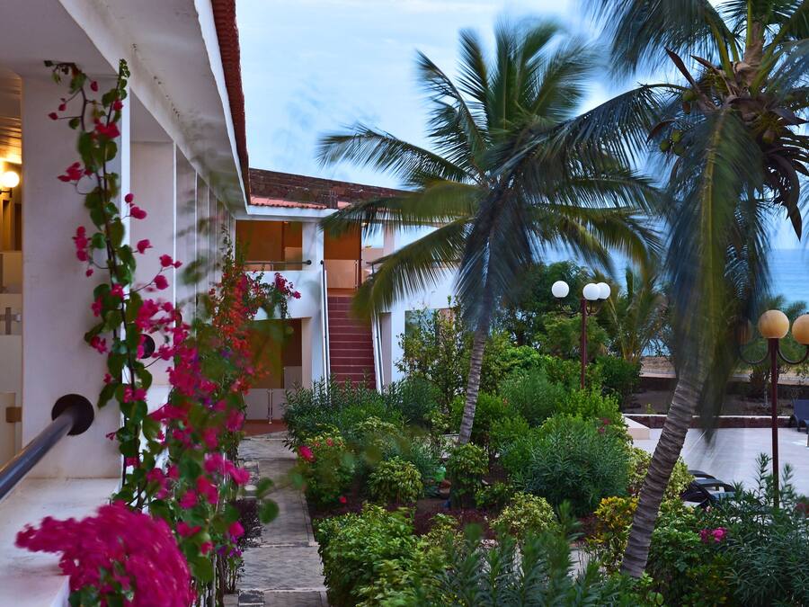 Un hotel con piscina, palmeras y una escalera adornada con flores rosadas.