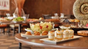 Une table de buffet proposant divers plats, notamment un saladier de fruits et des desserts.