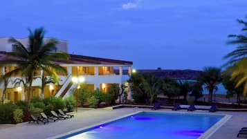 Una piscina al aire libre, sombrillas, sillones reclinables de piscina