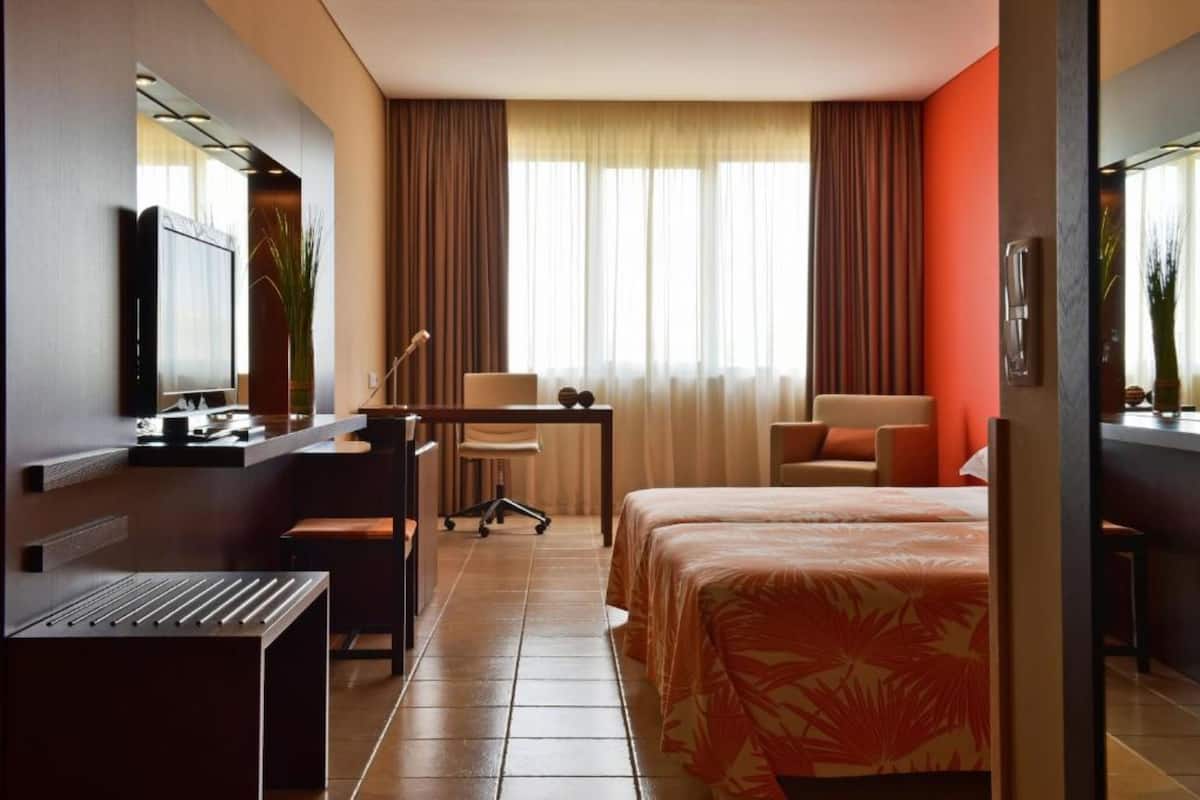 Een hotelkamer met een bed, bureau, stoel en televisie.