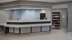 A reception area with a counter, a digital screen, and a shelf with snacks. - SpringHill Suites by Marriott Portland Hillsboro (Hillsboro)