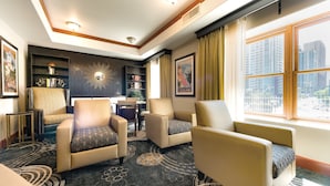 Habitación de hotel con zona de estar que incluye dos sillones, una mesita y una estantería.