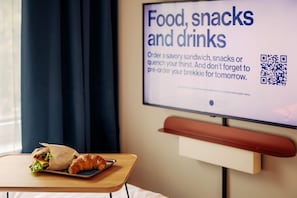 Habitación de hotel con una pantalla de televisión mostrando un menú de comida, aperitivos y bebidas.