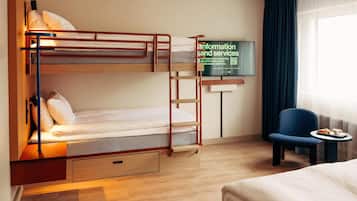 A bunk bed with a ladder, a desk with a chair, a television, and a window with curtains.