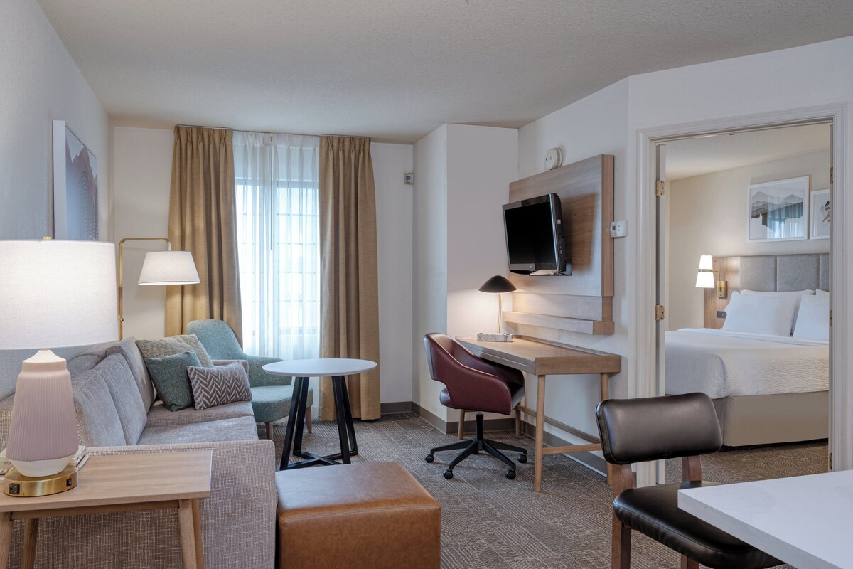 Une chambre d’hôtel équipée d’un canapé, d’un bureau, d’une chaise, d’un lit et d’une télévision.