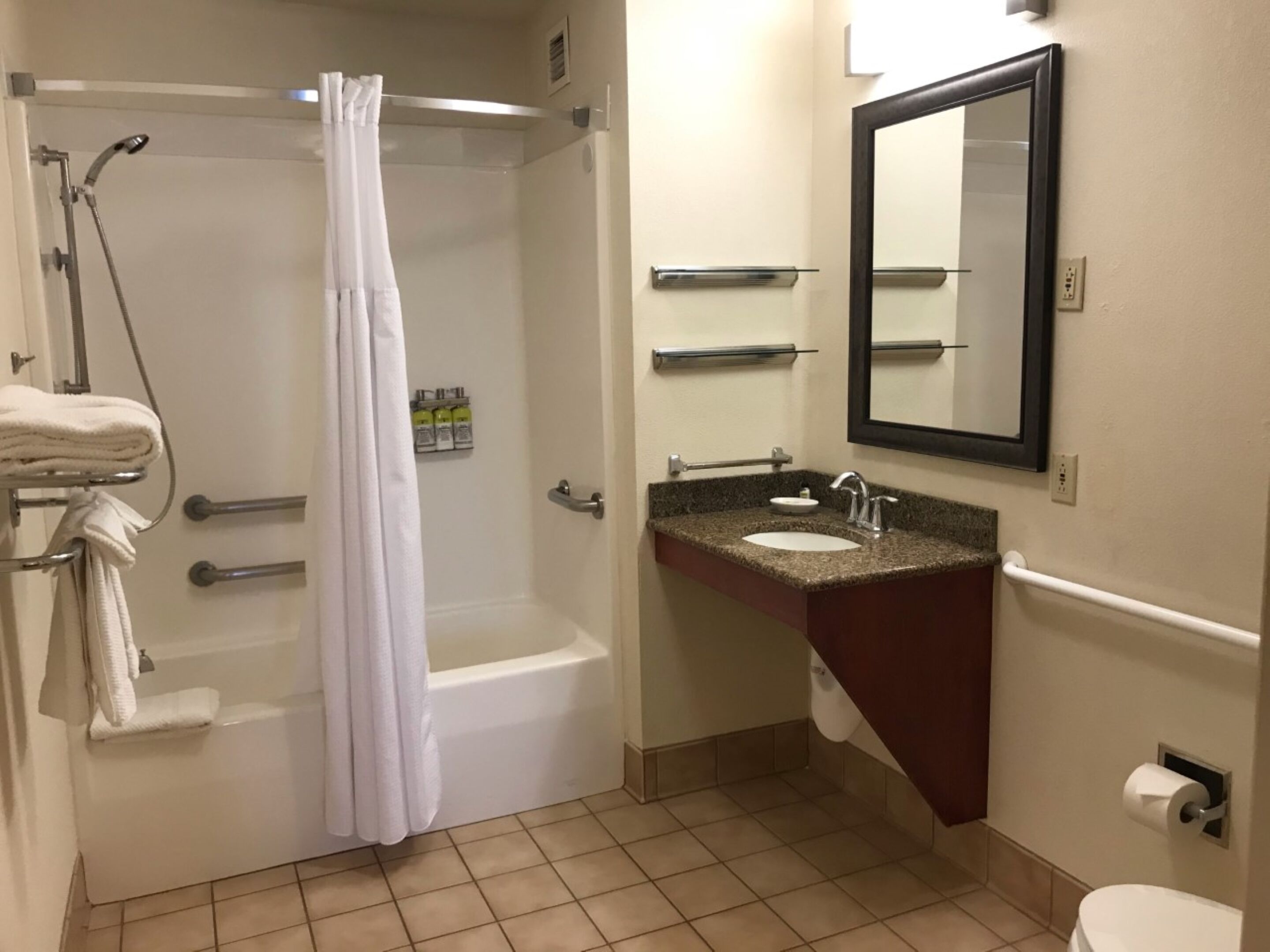 A bathroom with a bathtub, a sink with a mirror, and a toilet.