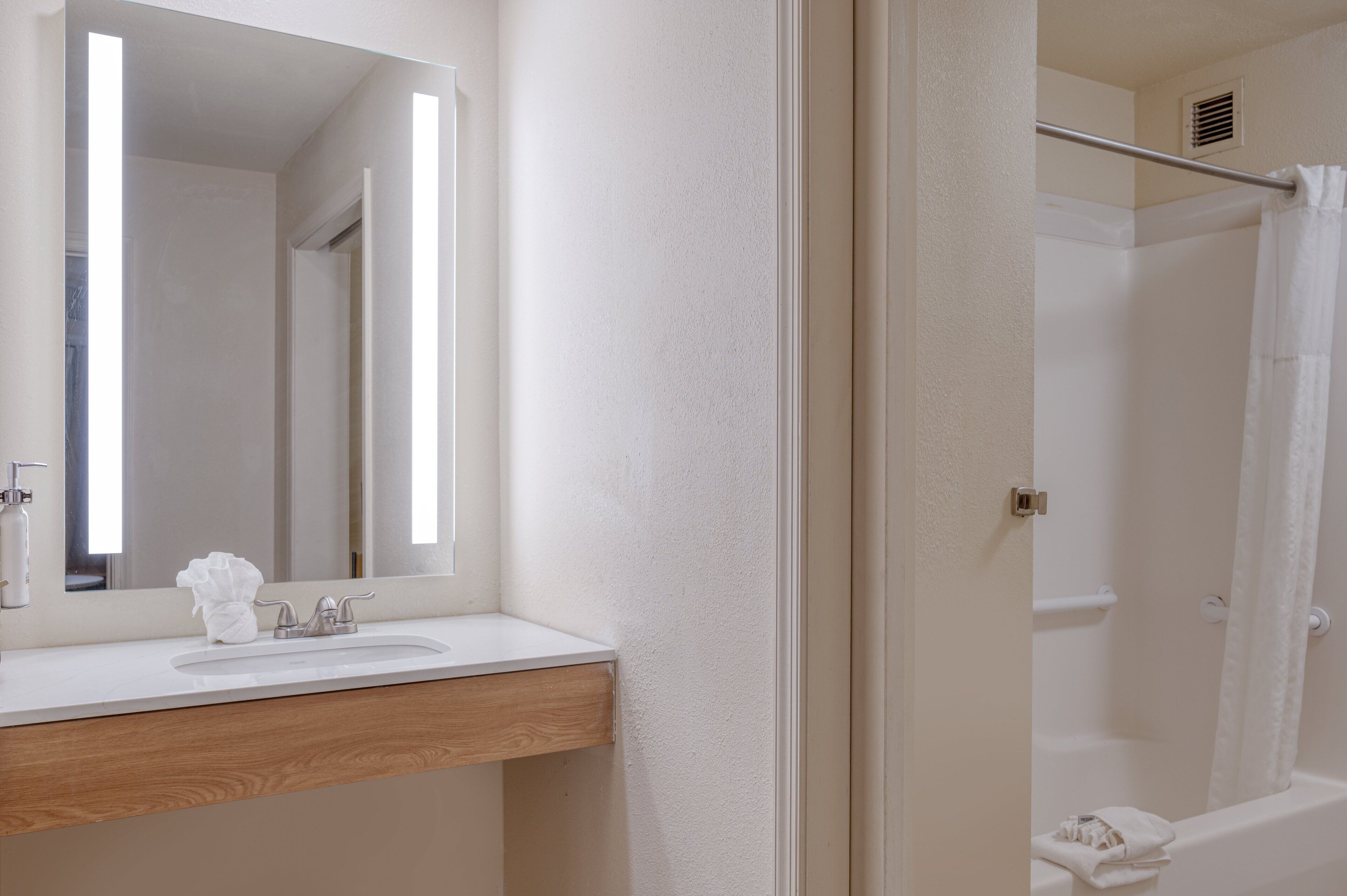Une salle de bain avec un lavabo blanc, un miroir et un espace douche.