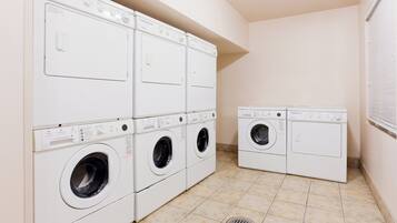 A laundry room with multiple Wascomat washing machines, a tiled floor, and a vented ceiling.